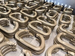 Several piles of tan plastic carabiner-style clips are arranged closely together on a wooden surface.