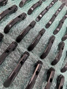 Rows of identical black metal components are arranged neatly on a sheet of green bubble wrap.