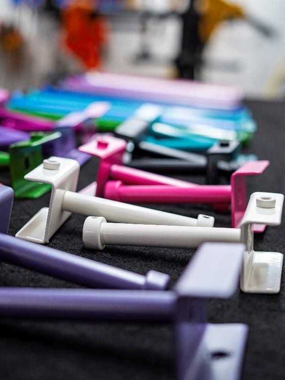 Colourful metal brackets and bolts are arranged on a dark surface, with a variety of colours including purple, white, pink, black, blue, and green visible.